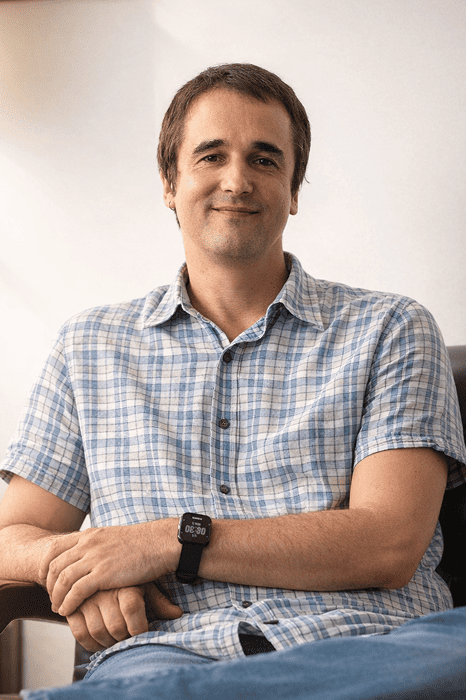 Photo of Gustavo. He is sitting cross-legged.